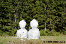 Deux bonhommes de neige de fonte dans l'herbe.