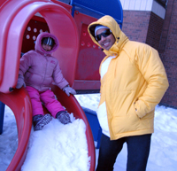 Child and adult covered up in the winter at the park.