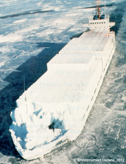 Un navire porte-conteneurs est presque complètement enveloppé de glace blanche épaisse en raison de la congélation des embruns qui a gelé sur la coque du bateau.