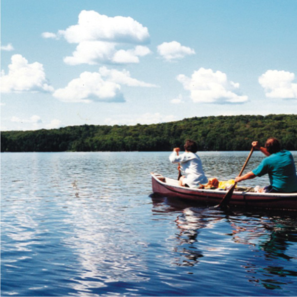 A few cumulus clouds above a family in a canoe on a lake